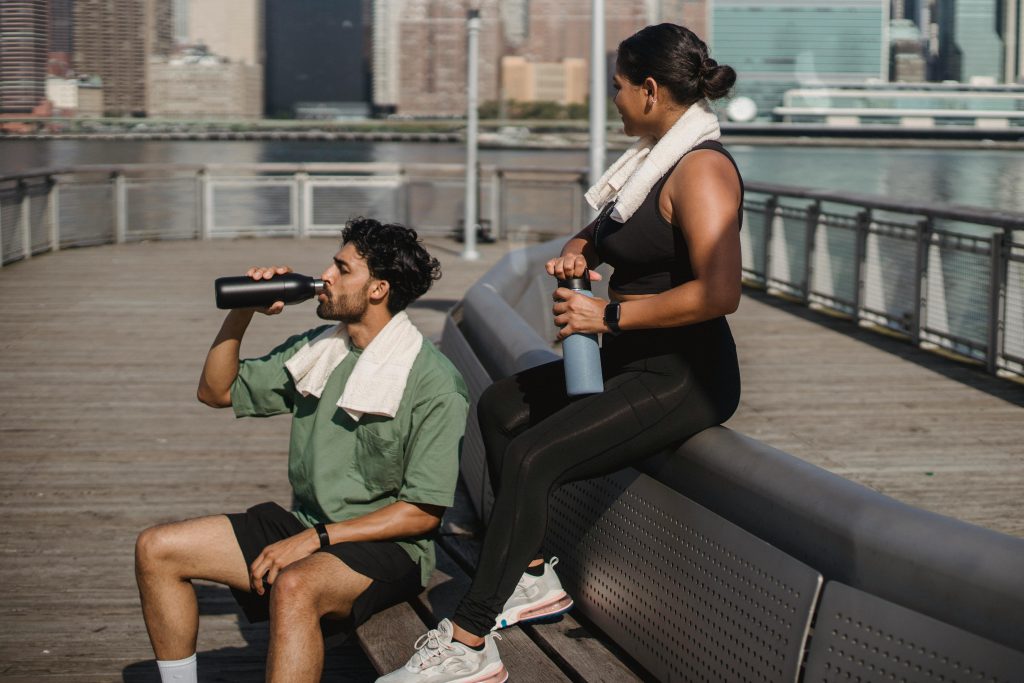 Dos personas descansando e hidratándose después de hacer ejercicio al aire libre
